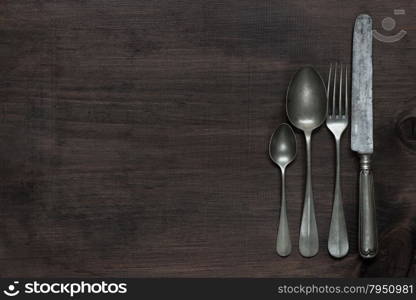 Row of vintage knife, fork and spoons on old wooden boards