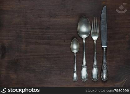 Row of vintage knife, fork and spoons on old wooden boards
