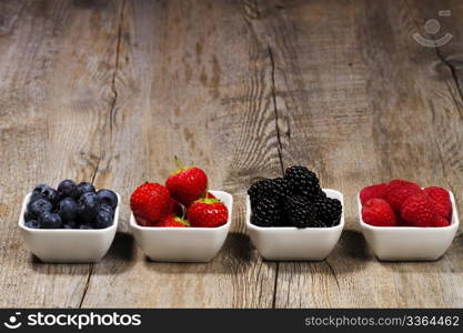 row of wild berries in bowls. row of wild berries in bowls on wooden background