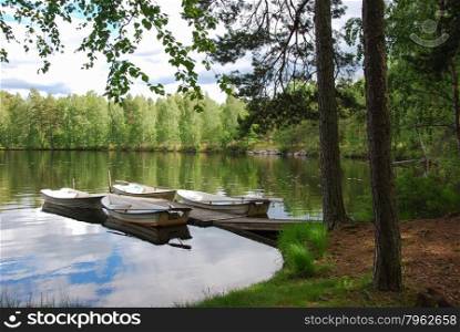 Rowing boats by an old wooden pier in a calm bay in a swedish lake in the woodlands