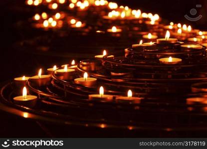 Rows of burning candles in a cathedral