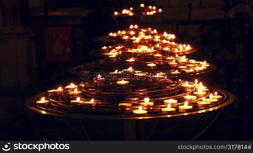 Rows of burning candles inside a cathedral