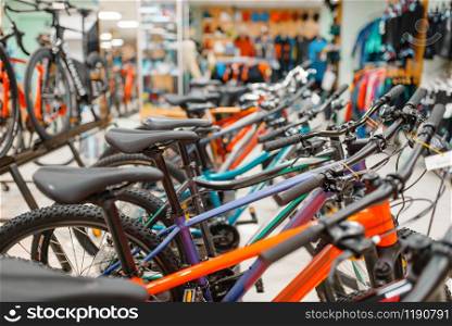 Rows of mountain bicycles in sports shop, focus on seat, nobody. Summer active leisure, showcase with bikes, cycle sale. Rows of bicycles in sports shop, focus on seat