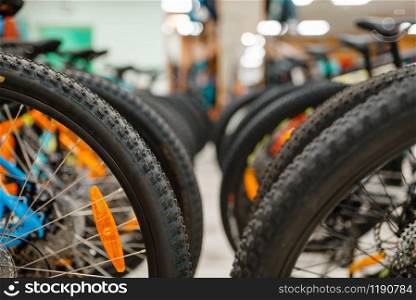 Rows of mountain bicycles in sports shop, focus on wheels, nobody. Summer active leisure, showcase with bikes for extreme riding, cycle sale. Rows of cycles in sports shop, focus on wheels