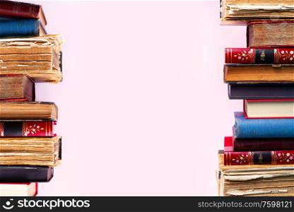 Rows of old antique books on pink background with copy space. Pile of old books