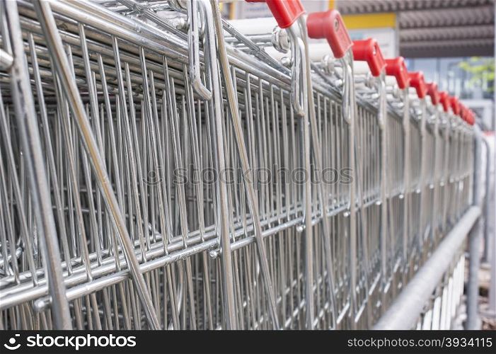 Rows of shopping carts on car park near entrance of supermarket