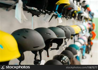 Rows of ski and snowboarding helmets in sports shop, nobody. Winter active leisure, showcase with protect equipment. Rows of ski and snowboarding helmets, sports shop