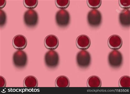 Rows with glasses of red wine alcohol drink on a pink background with hard shadows. Top view. Alcohol drink pattern.. Red wine glasses pattern with shadows. Top view.