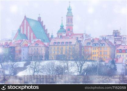 Royal Castle and colorful houses by the Vistula River in the snowy evening, Warsaw, Poland.. Old Town and river Vistula at night in Warsaw, Poland.