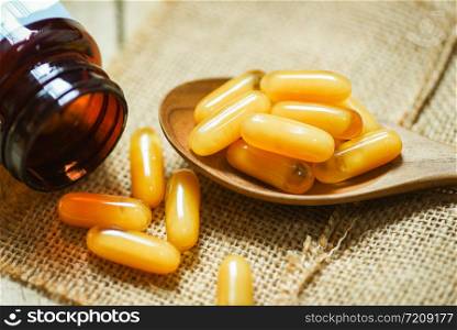 Royal jelly capsules in wooden spoon and sack background / Yellow capsule medicine or supplementary food from nature for health