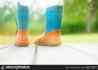 rubber boots on a wooden background. children&rsquo;s rubber boots on a background of green grass