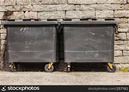 Rubbish recycling concept. Two black industrial trash cay dumpster containers, littler garbage. Two black industrial trash cay containers littler garbage