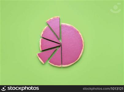 Ruby chocolate mousse tart with half whole and half cut in pieces, on green seamless background. Flat lay of pink chocolate pie with slices.