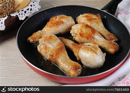 Ruddy fried chicken drumsticks in pan closeup