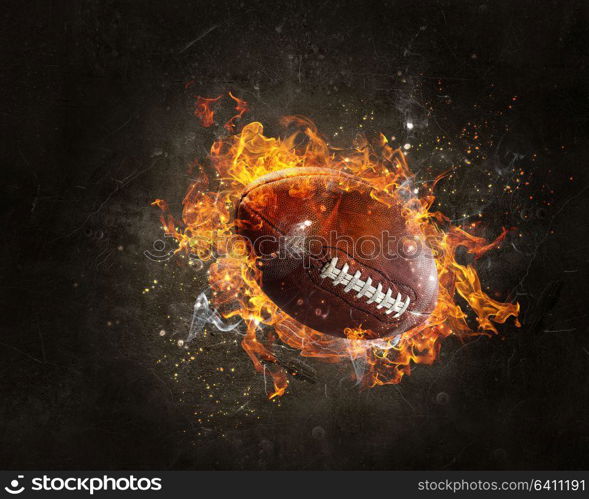 Rugby ball in a fire flames on dark background. Mixed media. American football game concept. Mixed media
