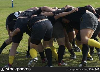 Rugby players forming scrum in a field
