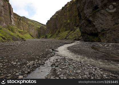 Rugged mountain canyon landscape with rocky riverbed and stream