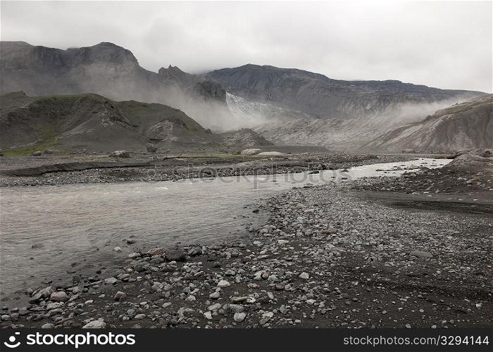 Rugged mountain landscape with river and mist rising