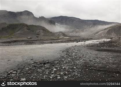 Rugged mountain landscape with river and mist rising