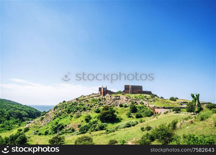 Ruin of a castle on the top af o green hill in the summer under a blue sky