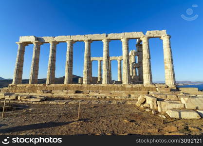 Ruins of an ancient temple of Poseidon at Greece Cape Sounio. Poseidon is the Greek god of the sea. Shot of temple ruins on sunset. Tourist landmark of Attica, Sounion, Greece.. Greece Cape Sounio. Ruins of an ancient temple of Poseidon, the Greek god of the sea, on sunset.