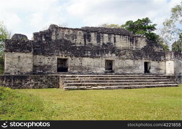 Ruins of big palace and square with green grass in Tikal