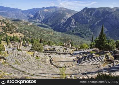 Ruins of the ancient theatre and Temple of Apollo at the archaeological site of Delphi, a UNESCO World Heritage Site, a religious sanctuary dedicated to the Greek god Apollo, on Mount Parnassos, with scenic views of valley below and mountains.