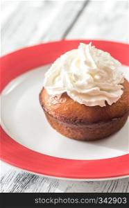 Rum baba decorated with whipped cream on the plate