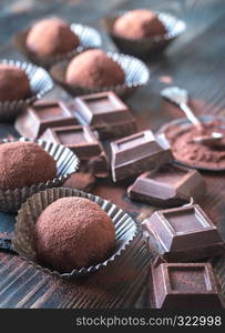 Rum balls with cocoa powder and chocolate slices on the wooden board