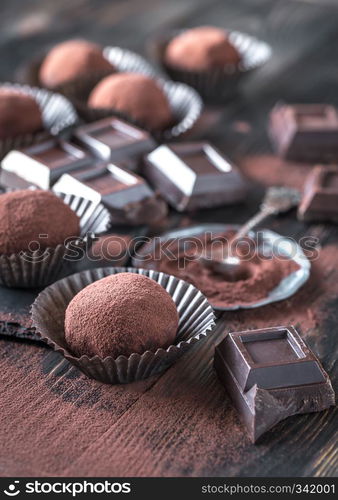 Rum balls with cocoa powder and chocolate slices on the wooden board