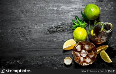 Rum with ice , mint and fresh lime. On a black wooden background.. Rum with ice , mint and fresh lime.