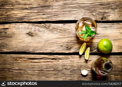 Rum with mint and lime. On wooden background.. Rum with mint and lime.