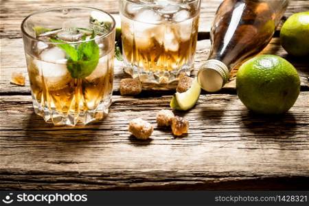 Rum with mint and lime. On wooden background.. Rum with mint and lime.