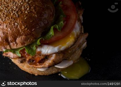 rumpled juicy cheeseburger on a black surface, top view, close - up. fast food on a black background
