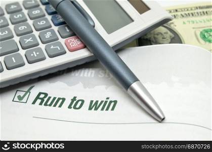 Run to win printed on book with calculator and pen.