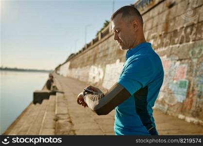 Runner checking smartwatch controlling pulsations after exercise. Sport and fitness, healthy running concept. Runner checking smartwatch controlling pulsations after exercise