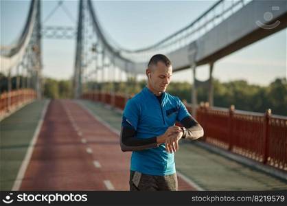 Runner checking smartwatch controlling pulsations after exercise. Sport and fitness, healthy running workout concept. Runner checking smartwatch controlling pulsations after exercise