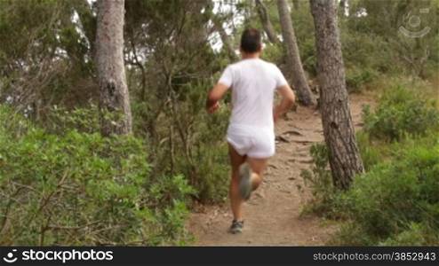 Runner doing sports through the field and up the Stones.Outdoor fitness exercises on the mountain.Healthy life doing outdoor sport.Runner training for a career.Sportsman climbing stones in a rocky mountain.