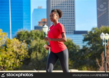 Runner girl running and listening music earphones in the city park