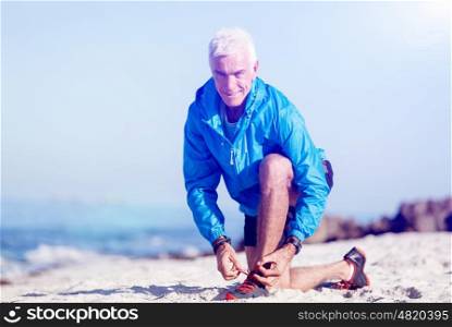 Runner laces his shoes and prepares to jogging. Male runner laces his shoes and prepares to jogging
