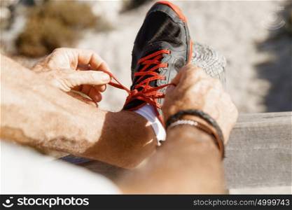 Runner laces his shoes and prepares to jogging. Male runner laces his shoes and prepares to jogging