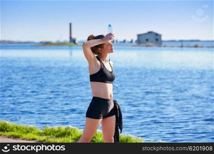 Runner woman relaxing after workout outdoor with water bottle in a lake