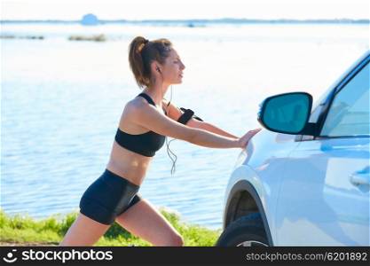 Runner woman stretching on a car in the lake outdoor