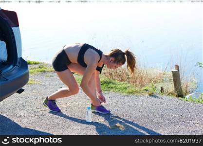 Runner woman stretching on a car in the lake outdoor