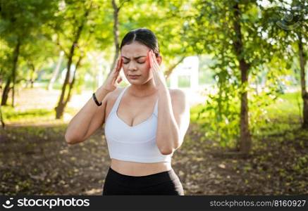 Runner woman with headache in a park. Athlete girl with migraine in a park. Young female runner rubbing her head with migraine in a park. Runner woman with headache and fatigue in the park