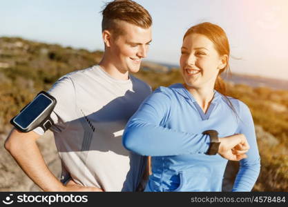 Runner woman with heart rate monitor running on beach. Young runner woman with heart rate monitor standing with her partner