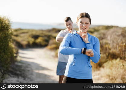 Runner woman with heart rate monitor running on beach. Young runner woman with heart rate monitor running on beach