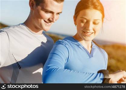 Runner woman with heart rate monitor running on beach. Young runner woman with heart rate monitor standing with her partner