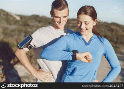 Runner woman with heart rate monitor running on beach. Young runner woman with heart rate monitor standing with her partner
