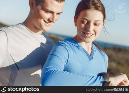 Runner woman with heart rate monitor running on beach. Young runner woman with heart rate monitor standing with her partner